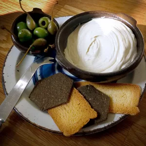 Classic creamy cashew vegan cheese by Mouse's Favourite served in a bowl with crackers and olives