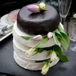 Special occasion vegan cheese by Mouse's Favourite - full wedding cake 4 layers of large wheels of cheese. Camembert, camblue and aged classic with cut flower decoration in between.